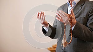 Praying hands of an old man with rosary beads