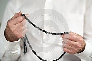 Praying hands of an old man with rosary beads