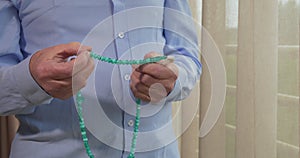 Praying hands of an old man with rosary beads