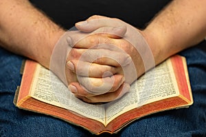 Praying Hands On An Old Open Bible