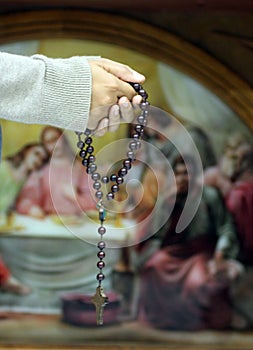 Praying hands with rosary on background of the last supper of Jesus. Holy week. Holy white Thursday concept