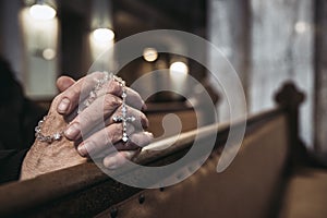 Praying hands with rosary in church