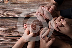 Praying hands on a wooden background with copy space, top table view