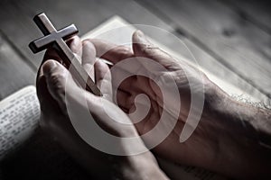 Praying holding religious crucifix cross with the bible