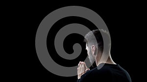 Praying man on black background, sins forgiveness, spiritual inspiration, help