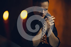 Praying priest. Portrait of priest Next to the candles prays