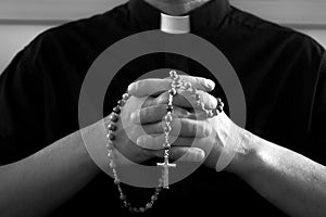 Praying priest with rosary beads