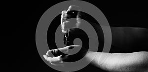 Praying with a rosary. hand of Catholic man with rosary on black background