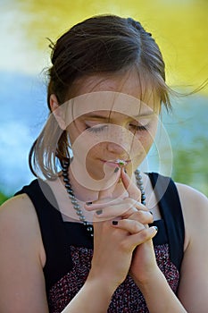 Praying teenage girl outside in nature