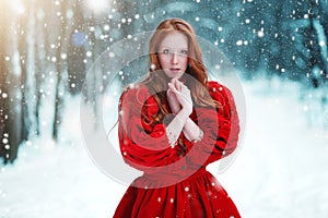 Praying woman in red dress in winter. Fairy tale girl over winter landscape.
