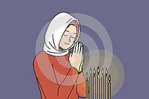 Praying woman stands in orthodox church near altar with candles and reads prayer