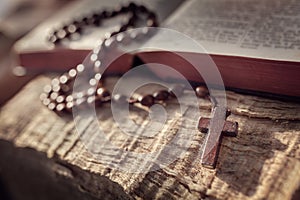 Praying with wooden rosary beads crucifix cross on Holy Bible background