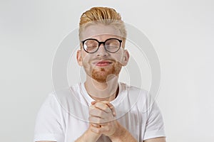 Praying young man isolated on white background. Copy space. Make a wish and fortune concept. Redheaded guy with red beard