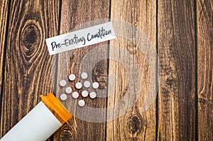 Pre-Existing Condition healthcare concept with pills on wooden board