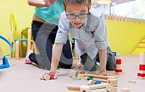 Pre-school boy wearing eyeglasses while playing with wooden toys
