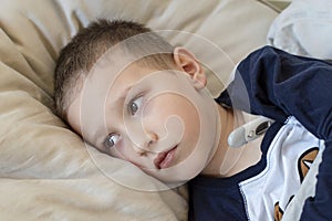 Pre-school sick boy lying in bed with a thermometer. Ill boy doesnâ€™t feel well. - Image