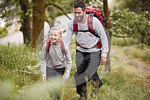 Pre-teen boy and his father hiking in a forest, selective focus