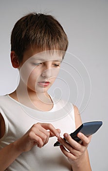 Pre-teen boy with mobile phone on light background