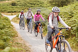 Pre-teen boy riding mountain bike with his sister and parents during a family camping trip, close up photo