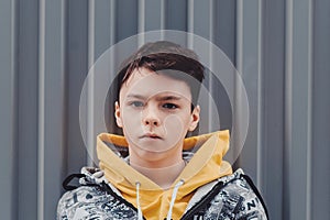 Pre-teen boy on a street in a big city next to a high-rise building alone.