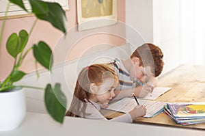 Pre-teen boy and young girl brother and sisterl focusing on their school work during homeschooling during coronavirus lockdo