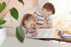 Pre-teen boy and young girl brother and sisterl focusing on their school work during homeschooling during coronavirus lockdo
