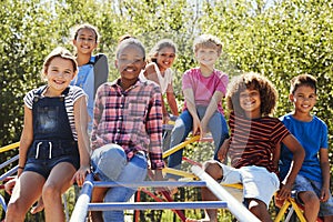 Pre-teen friends sitting on climbing frame in playground