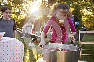 Pre-teen girl, apple in mouth, apple bobbing at garden party