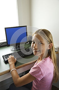 Pre-teen girl at computer smiling.
