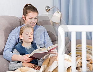 Pre-teen girl and mother reading book