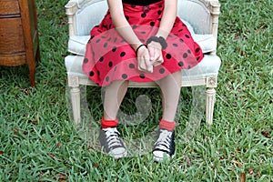 Pre-teen Girl Rests in Chair with Party Dress and Converse Tennis Shoes