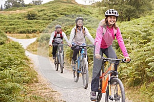 Pre-teen girl riding mountain bike with her parents during a family camping trip, close up