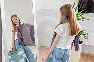 Pre-teen Girl Trying On Sweaters, Mirror Reflection. Morning preparation before school