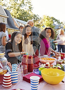 Pre-teen girls smiling to camera at a block party food table