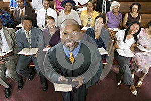 Preacher Holding Bible With Congregation Sitting In Church