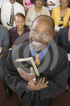 Preacher Holding Holy Bible With Congregation Sitting In Church