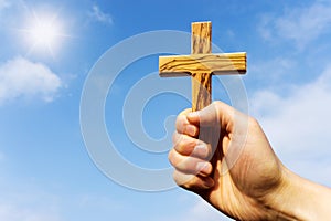 Preacher holding wooden cross against blue sky