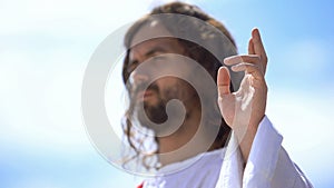 Preacher showing blessing sign against blue sky, hand of benediction, baptism