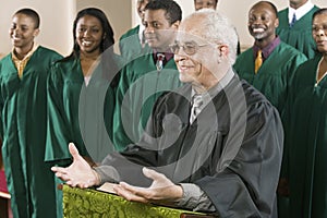 Preacher Standing At Pulpit With Choir In Background At Church