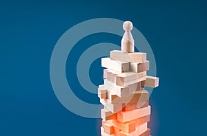 Precarious business situation concept with wooden human figurine standing on wooden blocks