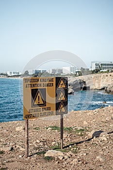 Precaution sign about dangerous edge near sea caves in Ayia Napa, Cyprus