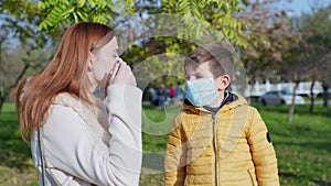 Precautions, mother puts medical mask on son and on her face during coronavirus pandemic