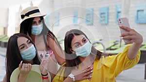 Precautions, young girls in medical masks taking selfie using a mobile phone during summer holidays