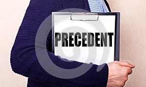 The PRECEDENT is written on a white sheet held by a man standing sideways