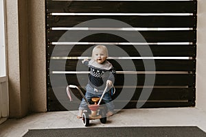 Precious Adorable Cute Little Blonde Baby Toddler Boy Kid Playing Outside on Wooden Toy Bicycle Scooter Mobile Smiling at the Came