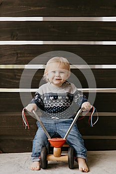 Precious Adorable Cute Little Blonde Baby Toddler Boy Kid Playing Outside on Wooden Toy Bicycle Scooter Mobile Smiling at the Came