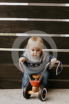 Precious Adorable Cute Little Blonde Baby Toddler Boy Kid Playing Outside on Wooden Toy Bicycle Scooter Mobile Smiling at the Came