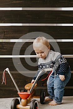 Precious Adorable Cute Little Blonde Baby Toddler Boy Kid Playing Outside on Wooden Toy Bicycle Scooter Mobile Smiling at the Came