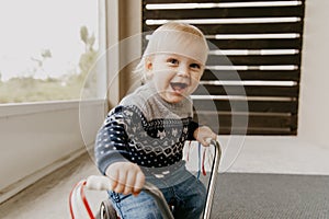 Precious Adorable Cute Little Blonde Baby Toddler Boy Kid Playing Outside on Wooden Toy Bicycle Scooter Mobile Smiling at the Came