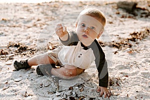 Precious Adorably Cute Happy Baby Boy Toddler Smiling and Playing in the Sand At the Beach Next to the Ocean Water Outside During